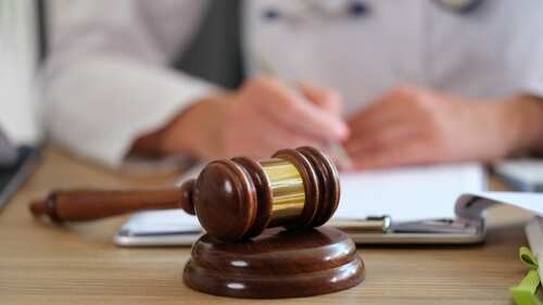 Wooden,Gavel,Of,Judge,On,Table,Close-up,,And,Blurred,Doctor