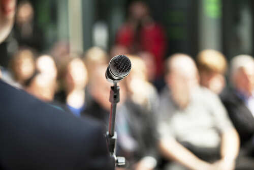 Microphone,In,Focus,Against,Blurred,Audience