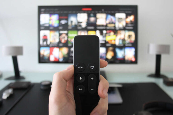Hand,Holding,A,Tv,Remote,While,Watching,Shows,On,A