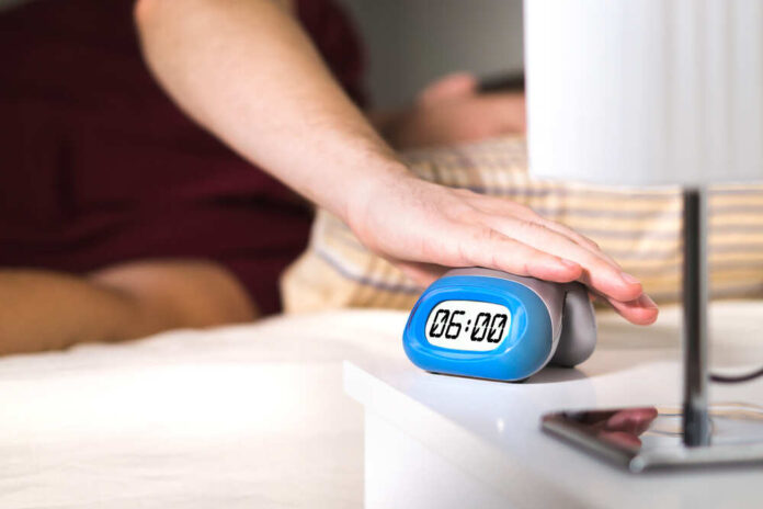 Man,Waking,Up,In,Bed.,Turning,Off,Alarm,Clock,On