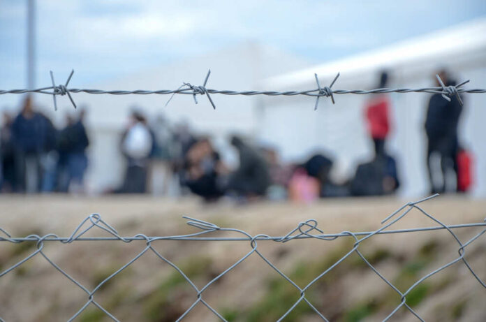 Barbed,Wire,In,Refugee,Camp.,Migrants,Behind,Chain,Link,Fence