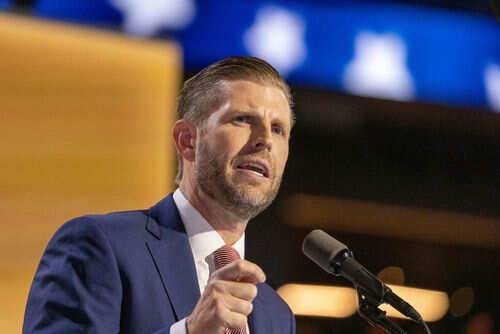 Man in suit speaking at a microphone indoors