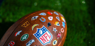 NFL football with team logos on grass field.