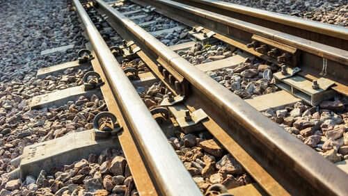 Railway tracks with rocks underneath in sunlight