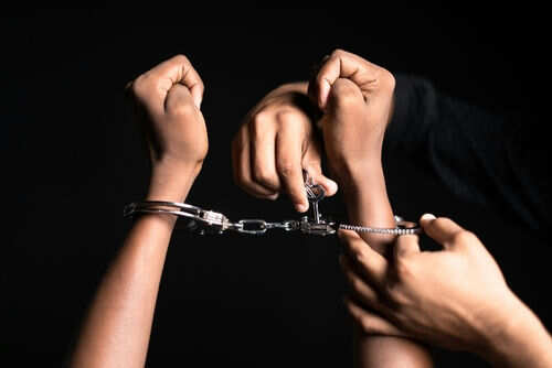 Hands in handcuffs being unlocked with key