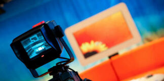 Television camera filming a colorful studio set