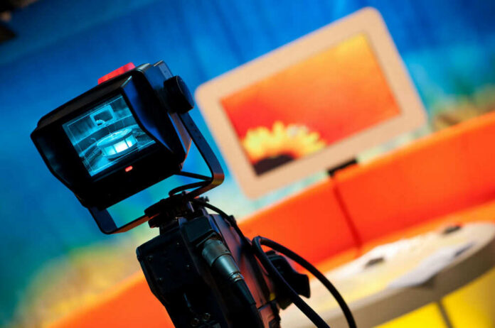 Television camera filming a colorful studio set