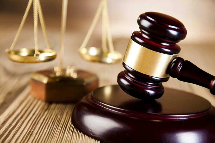 Wooden gavel and scales of justice on table