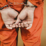 Person in orange jumpsuit with handcuffs behind back