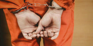 Person in orange jumpsuit with handcuffs behind back