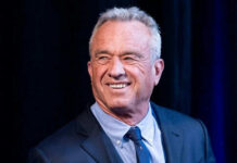 RFK Jr.’s SURPRISING Food Crackdown—Is Your Grocery Safe? Smiling man wearing a suit against dark background.