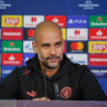Football manager at a press conference with branding in the background