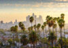 View of Los Angeles skyline with palm trees in the foreground during sunset