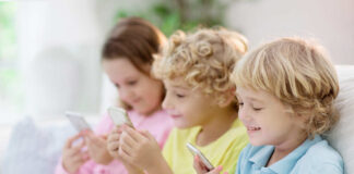 Three children sitting together, each using a smartphone