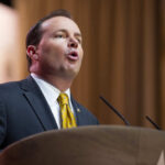 A man in a suit delivering a speech at a podium