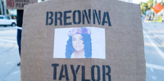 A protester holding a sign with the name Breonna Taylor and her image