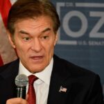 A man speaking into a microphone with an American flag pin on his suit