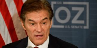 A man speaking into a microphone with an American flag pin on his suit