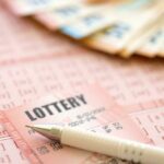 Close-up of lottery tickets and cash with a pen