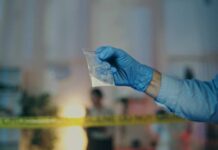 A gloved hand holding a plastic bag containing a suspicious substance at a crime scene