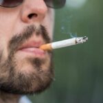 Close-up of a man smoking a cigarette while wearing sunglasses