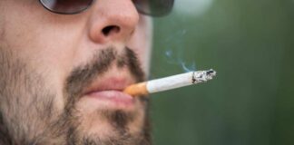 Close-up of a man smoking a cigarette while wearing sunglasses