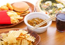 A variety of fast food items including fries, a burger, pizza, noodles, and a drink