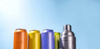 A lineup of colorful beverage cans next to a cocktail shaker and jigger