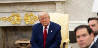 A serious-looking man in a suit sitting in a presidential office during a meeting