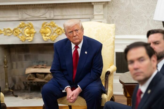 A serious-looking man in a suit sitting in a presidential office during a meeting