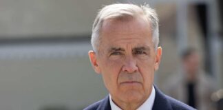 A man in formal attire with a serious expression outdoors