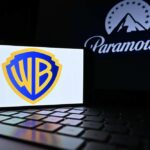Warner Bros logo displayed on a smartphone with Paramount logo in the background