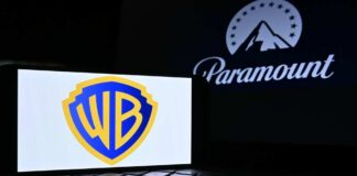 Warner Bros logo displayed on a smartphone with Paramount logo in the background