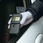 A police officer holding a breathalyzer device during a traffic stop