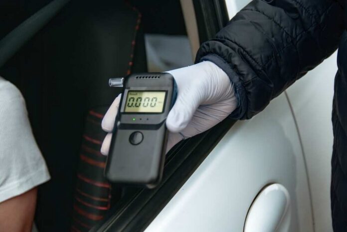 A police officer holding a breathalyzer device during a traffic stop