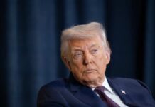 A serious-looking man in a suit during a public appearance