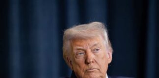 A serious-looking man in a suit during a public appearance