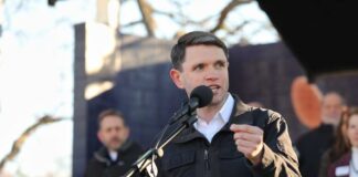A speaker addressing an audience at an outdoor event with a microphone
