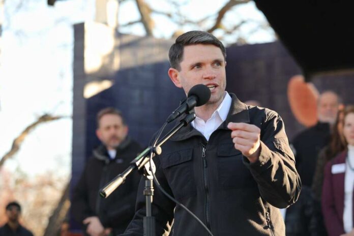 A speaker addressing an audience at an outdoor event with a microphone