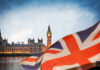 View of Big Ben and the Houses of Parliament with a British flag in the foreground