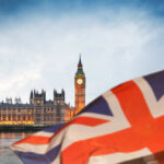 View of Big Ben and the Houses of Parliament with a British flag in the foreground