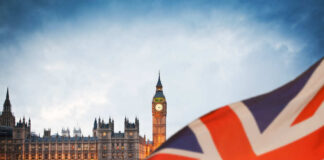 View of Big Ben and the Houses of Parliament with a British flag in the foreground
