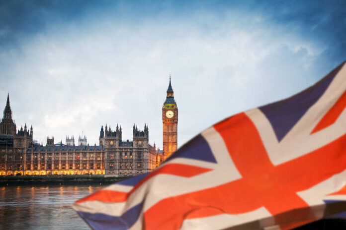 View of Big Ben and the Houses of Parliament with a British flag in the foreground