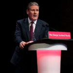 Trump TORCHES Starmer Over War Timing A man in a suit speaking at a podium.