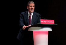A man in a suit speaking at a podium.
