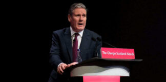 A man in a suit speaking at a podium.