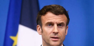 Man speaking at press conference with flags behind