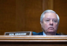 GOP’s Midterm NIGHTMARE: War and Shutdown Collide Man sitting at a desk with nameplate Sen Graham