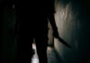 Silhouette of person holding knife in dark corridor