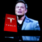 Red Tesla logo with blurred person in background